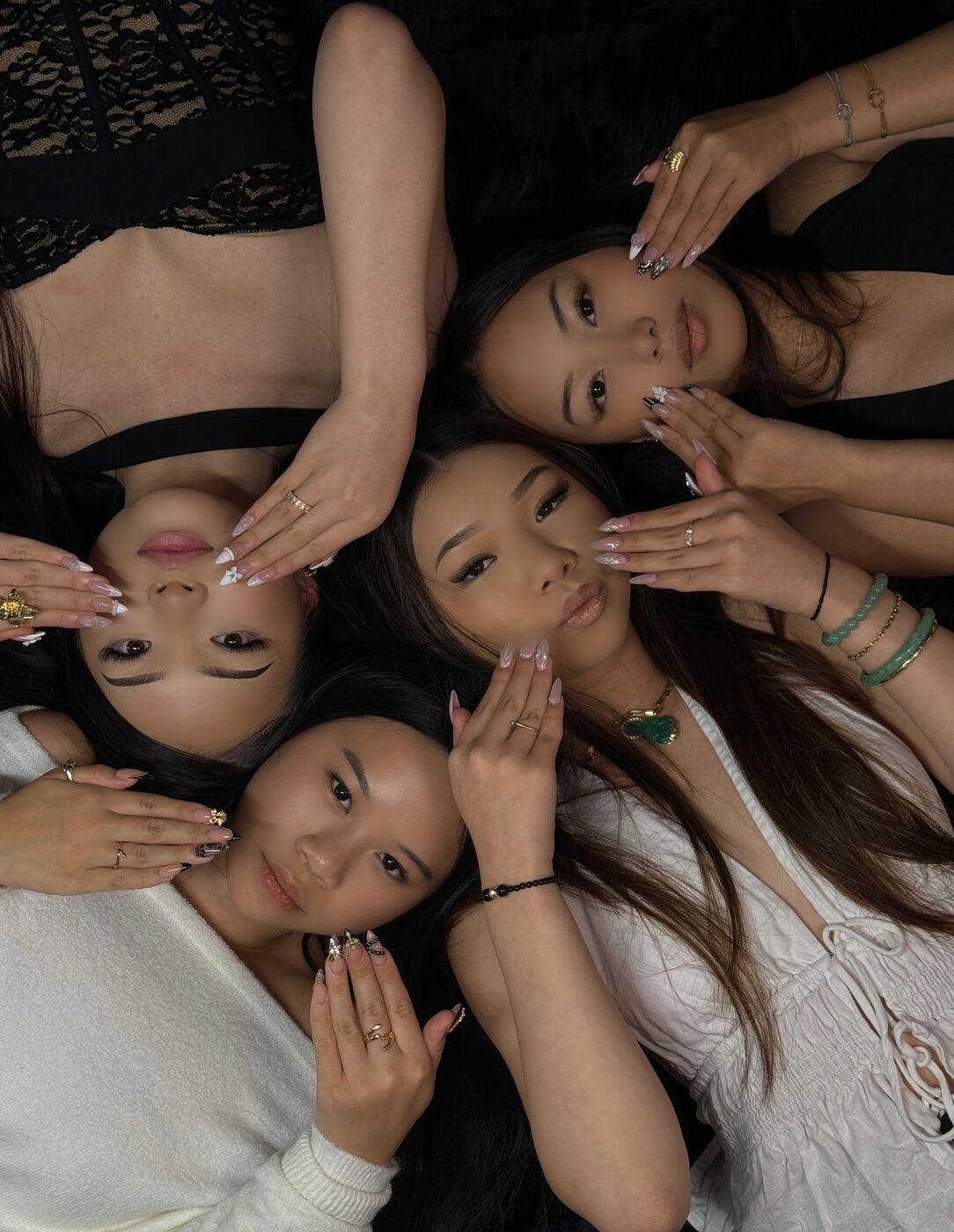 Five friends lying in a circle showing off fresh Novabeautytt nail sets and lashes